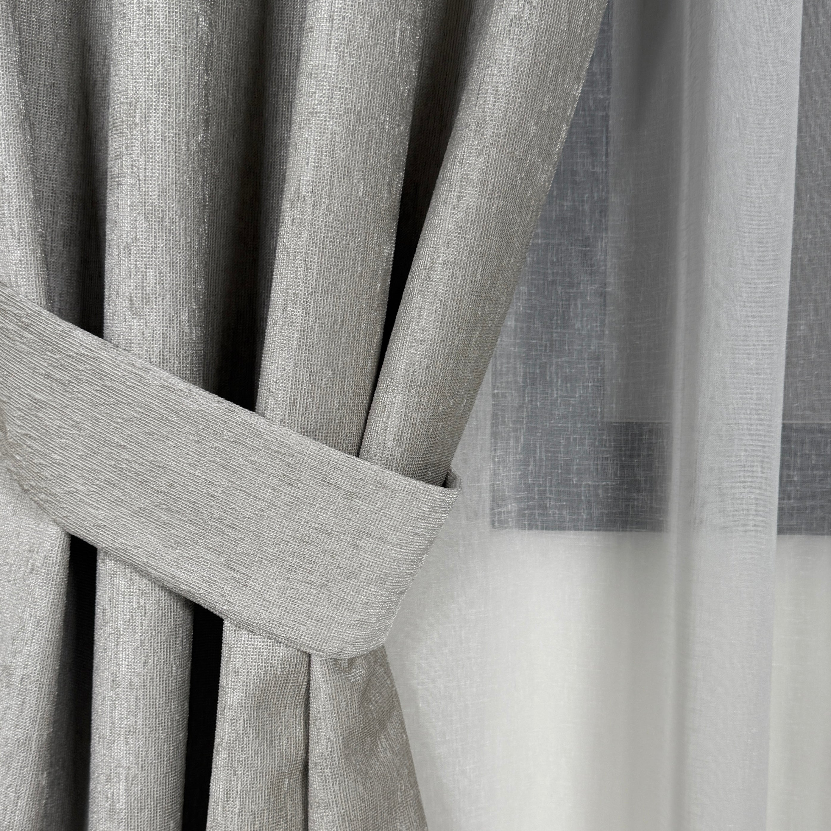 Close-up of gray curtains with a tieback
